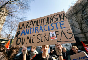 France, Paris, 2022-03-19. A demonstrator with a placard with the slogan The revolution will be anti-racist or it will not be". Demonstration against racism and police and prison violence. Photograph by Martin Noda / Hans Lucas France, Paris, 2022-03-19. Un manifestant avec une pancarte avec le slogan "La revolution sera antiraciste ou ne sera pas". Manifestation contre les racisme et les violences policieres et penitencieres. Photographie de Martin Noda / Hans Lucas